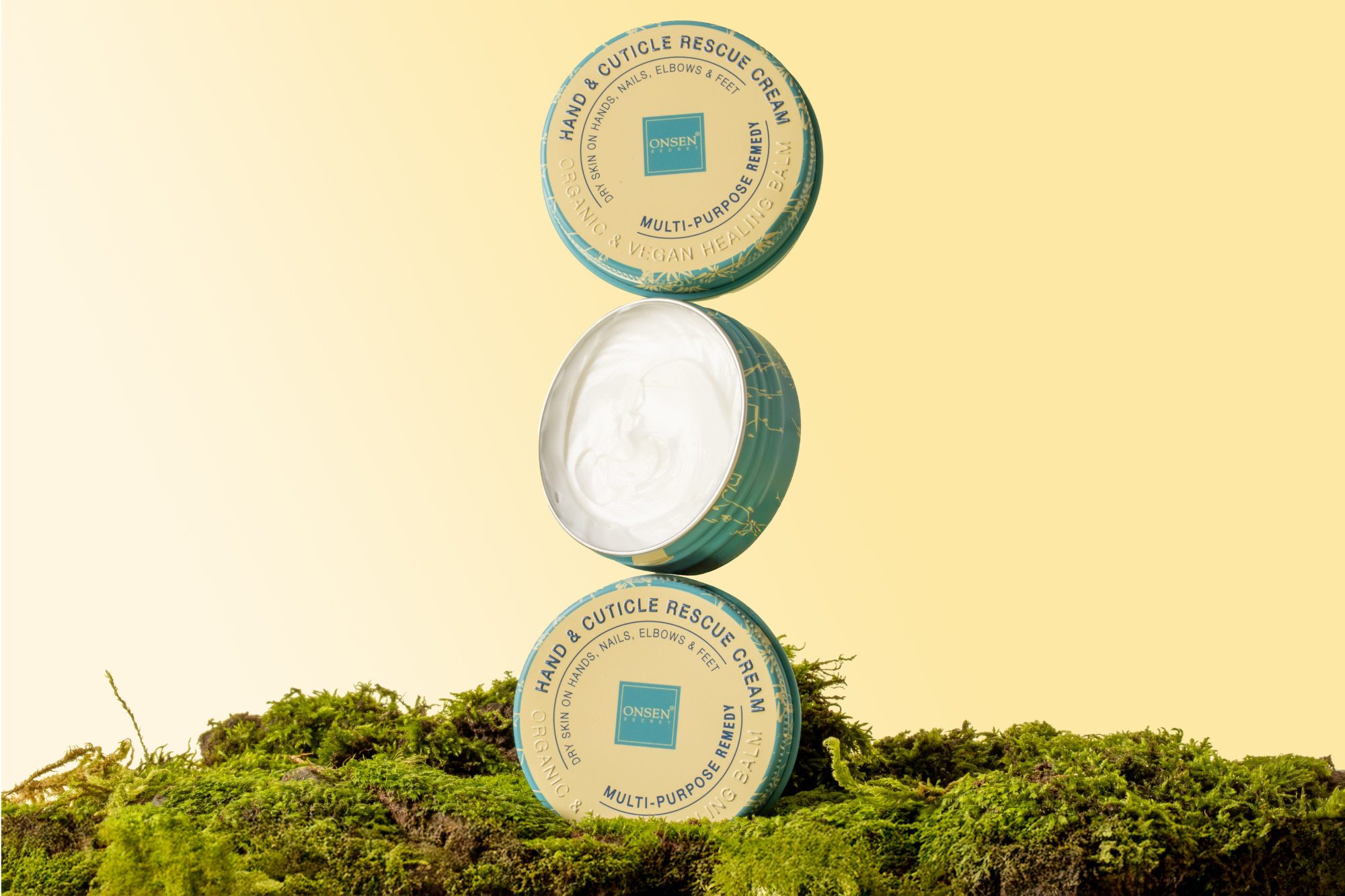 Three containers of hand and cuticle rescue cream on a grassy background