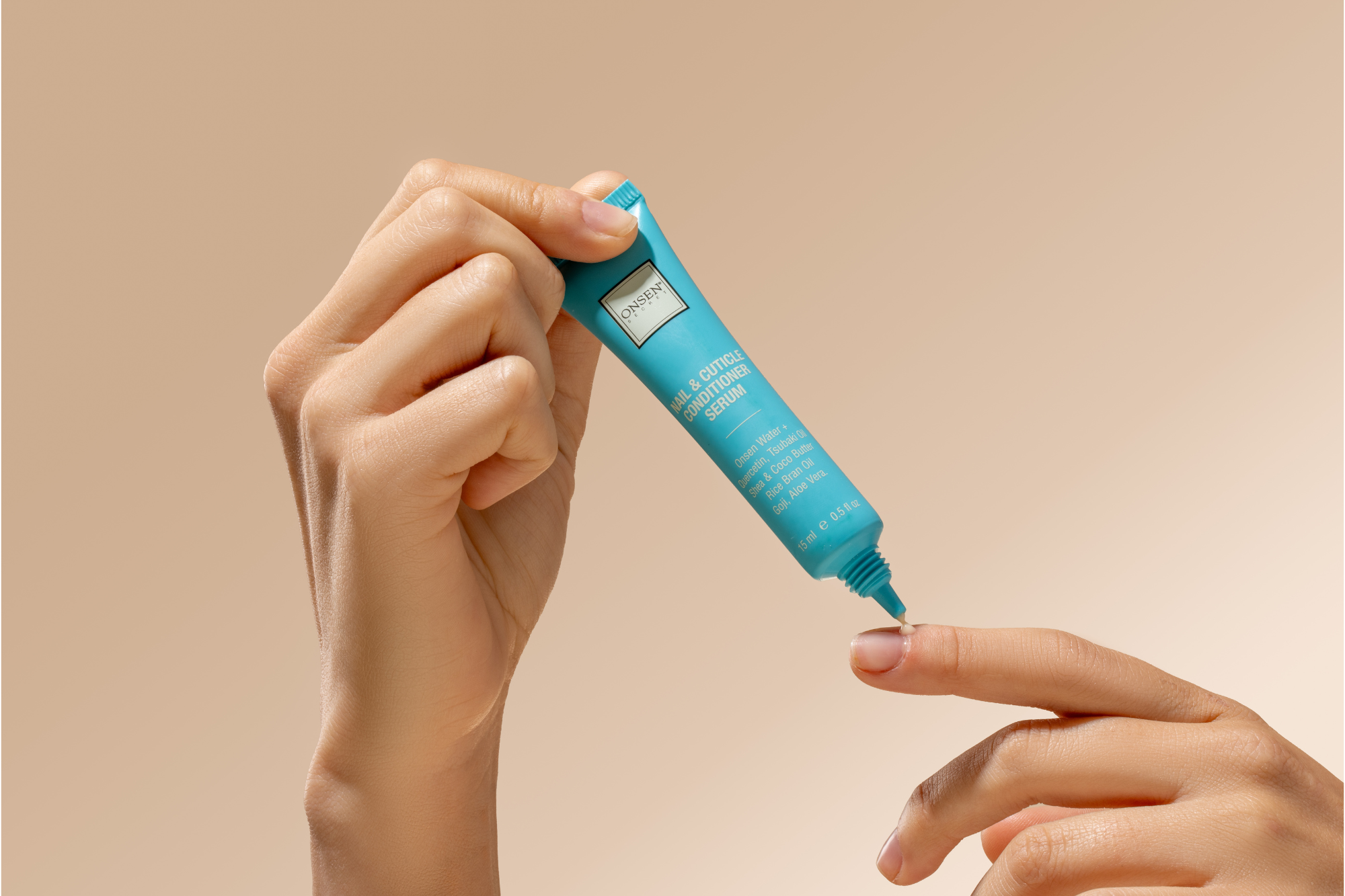 Hand applying a nail and cuticle conditioner serum to a finger against a beige background