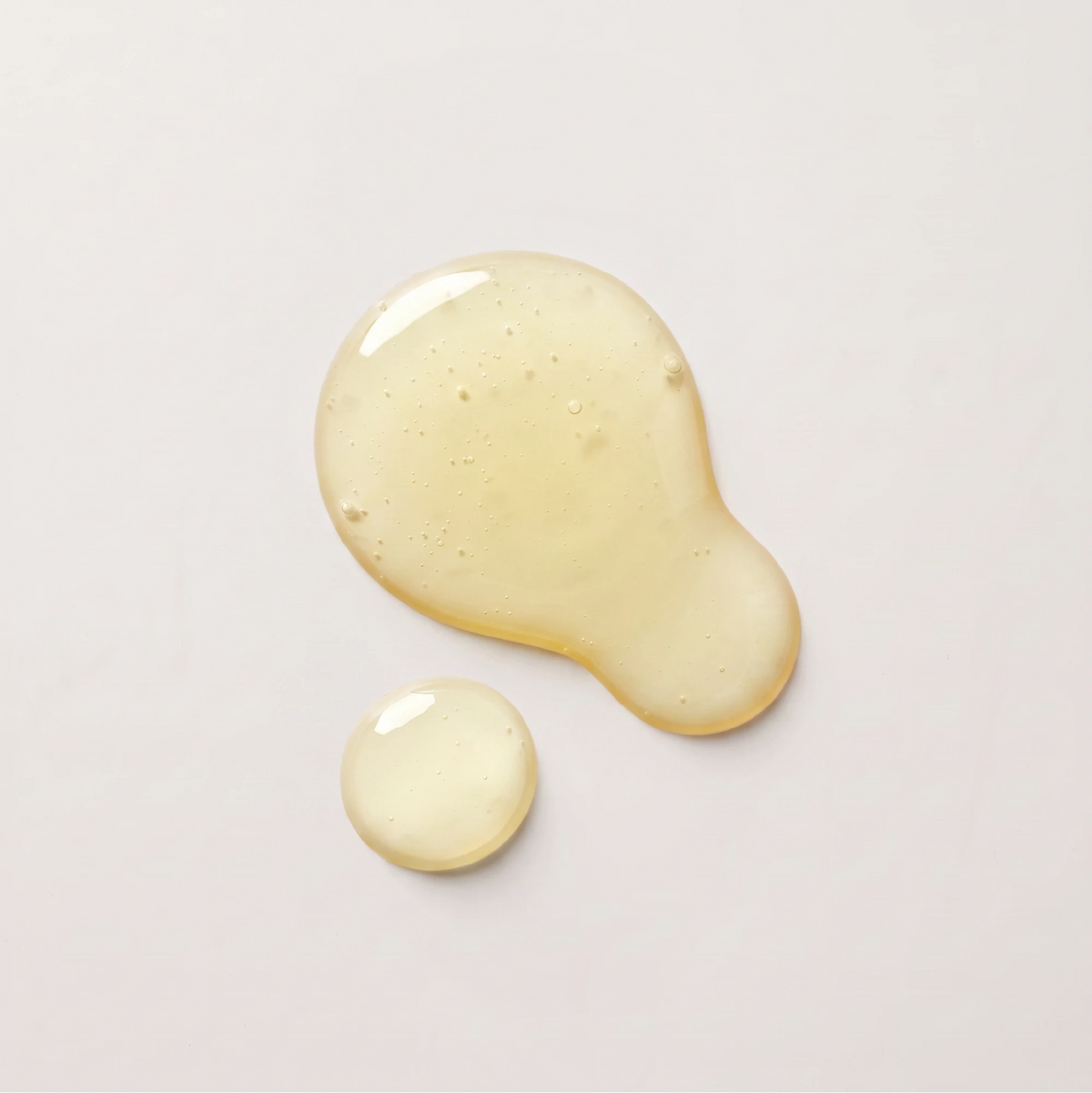 Nail care product texture visual, translucent golden oil drops showcasing Onsen Secret vegan nail reboot formula.