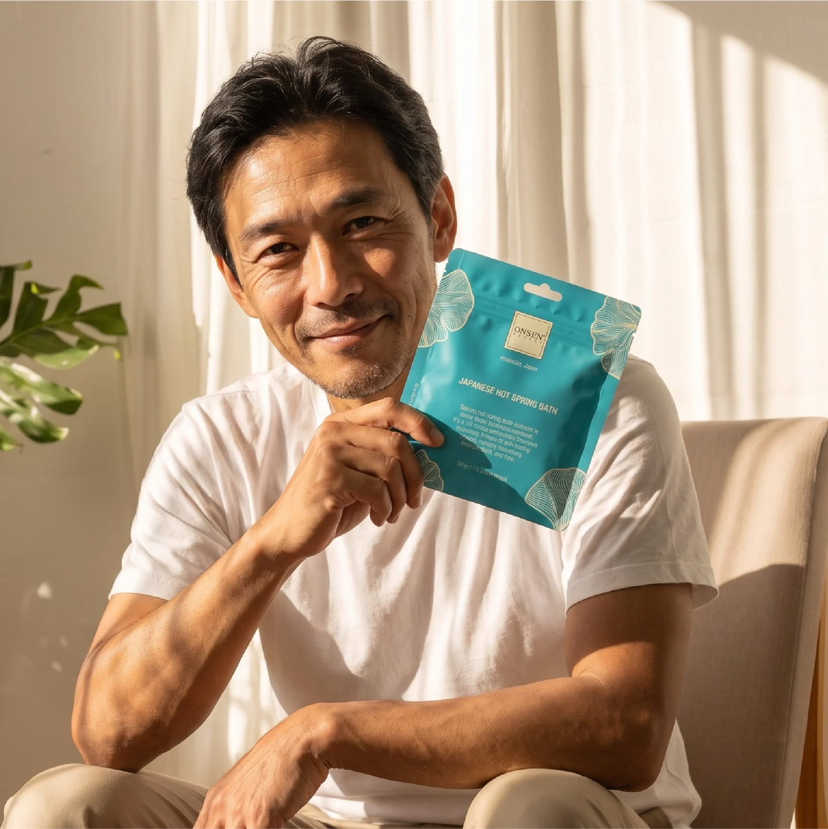 Onsen Secret Japanese Hot Spring Bath promotional image, teal package held near face emphasizing relaxation and self‑care benefits.