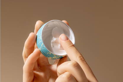 Hand holding a hand and cuticle rescue cream with a beige background